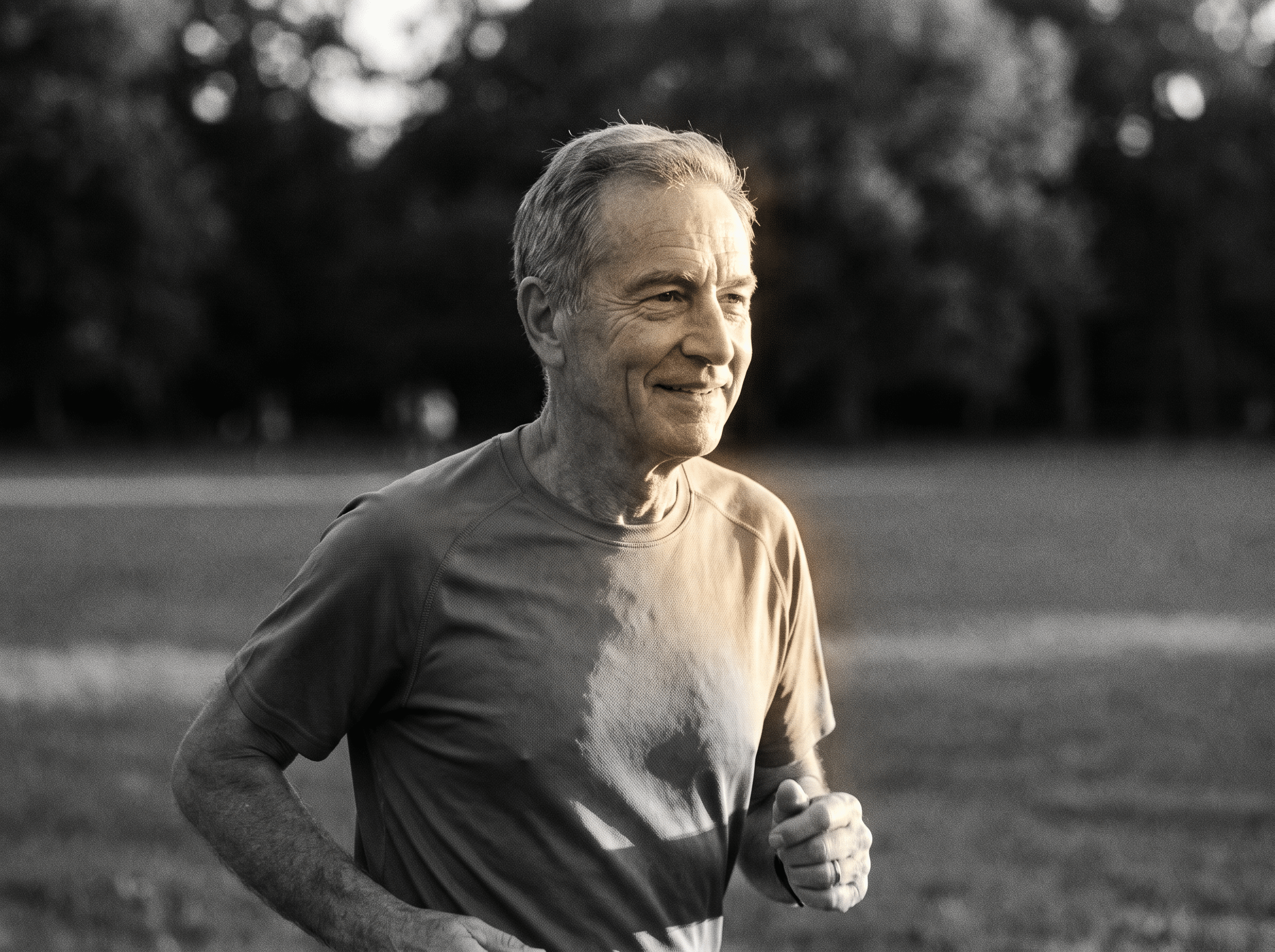 Homem mais velho correndo em um parque, sorrindo, representando longevidade e saúde.
